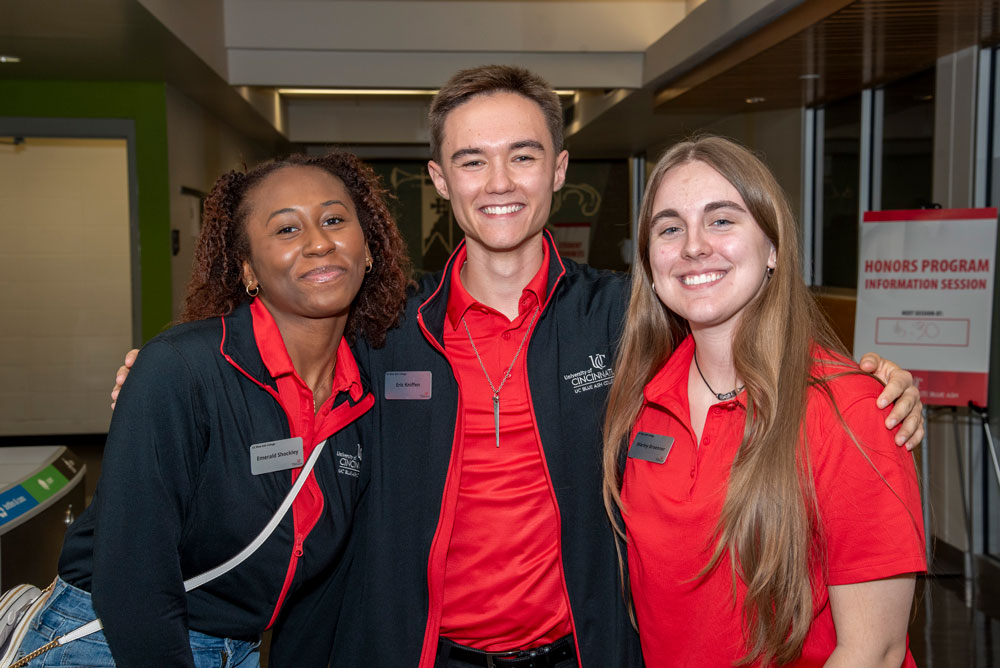 three smiling students in hallway