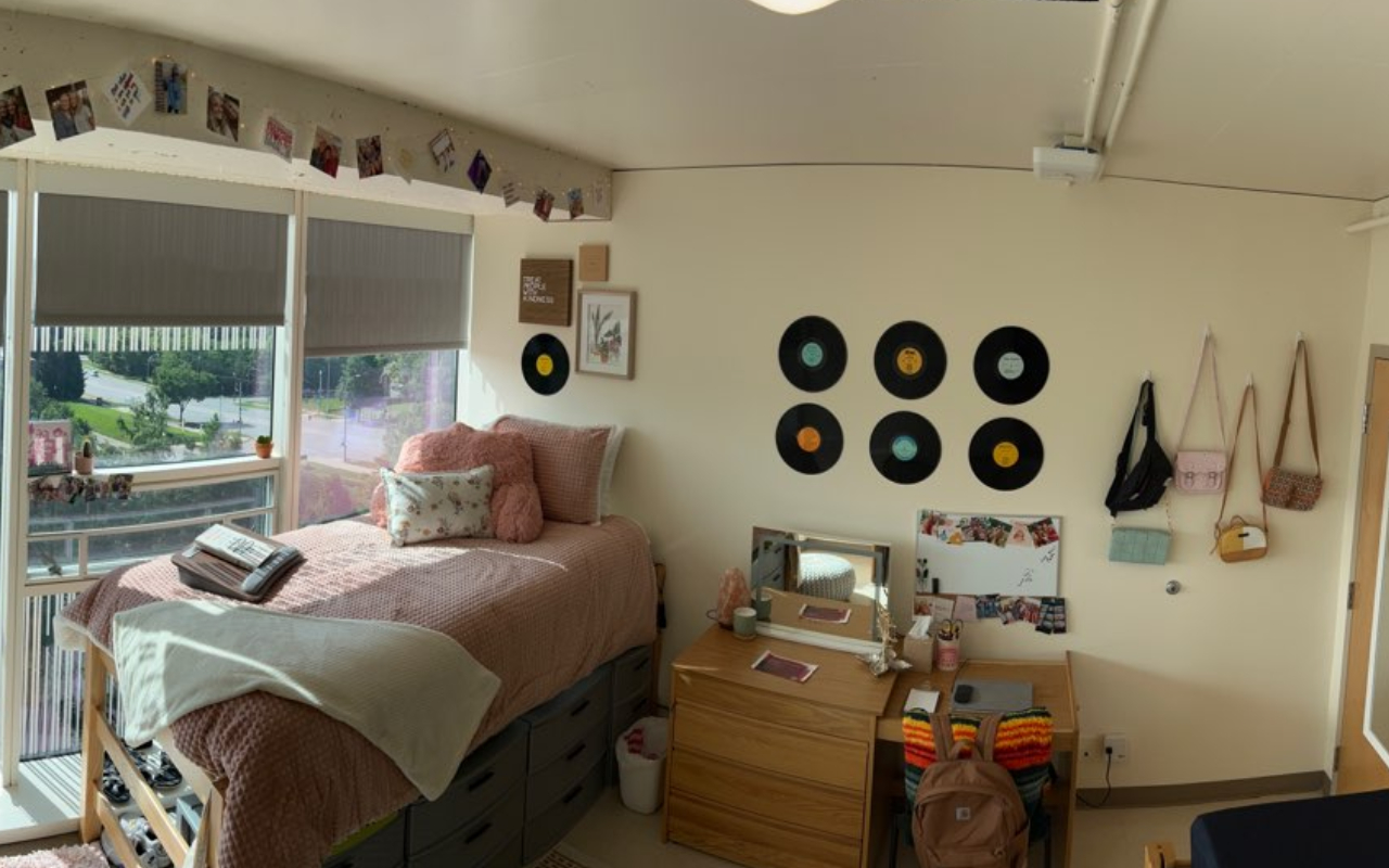 sample junior suite room showing a large window, raised bed, desk and wall of decorations.