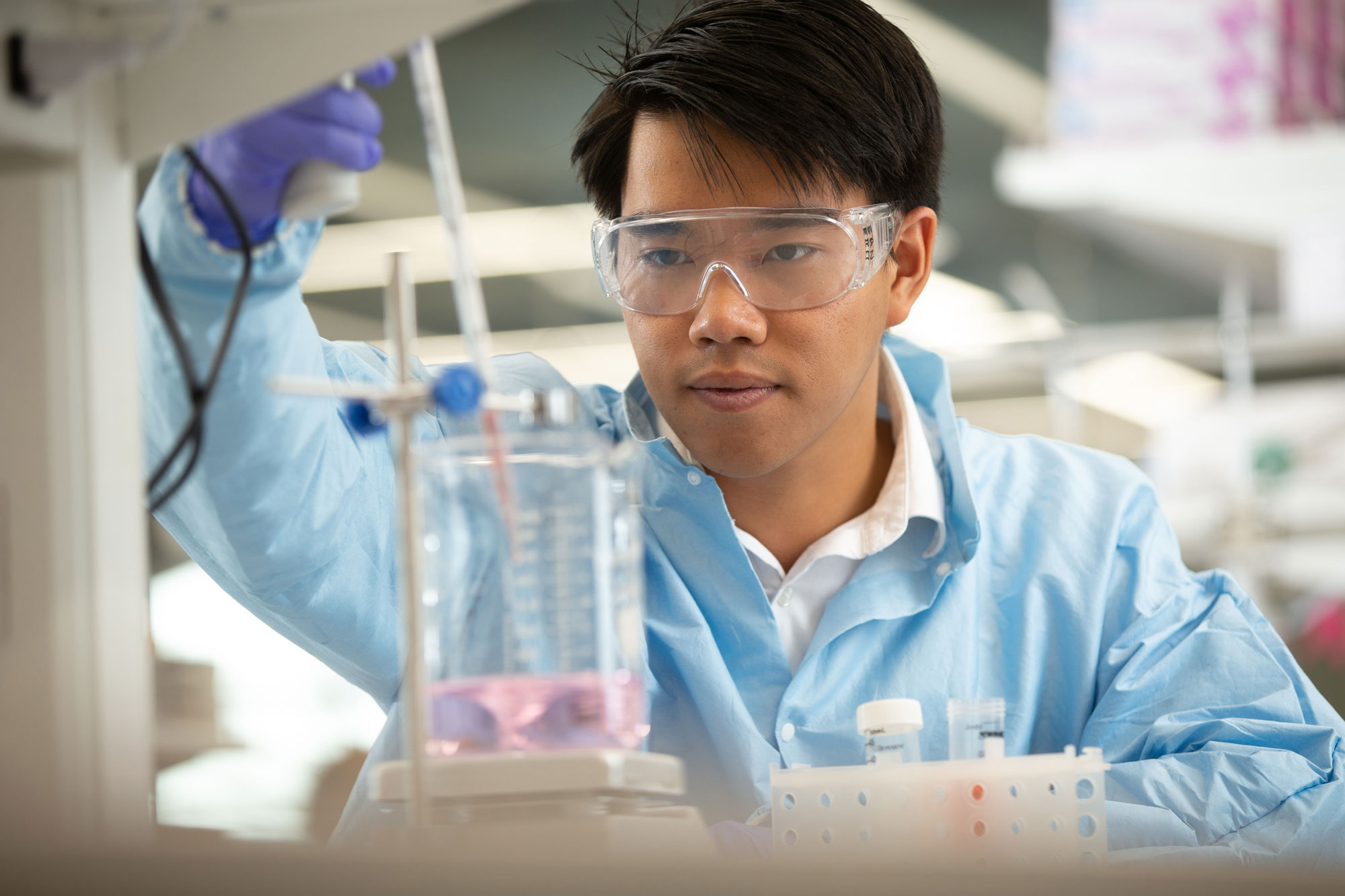 A University of Cincinnati student examines a beaker in a lab