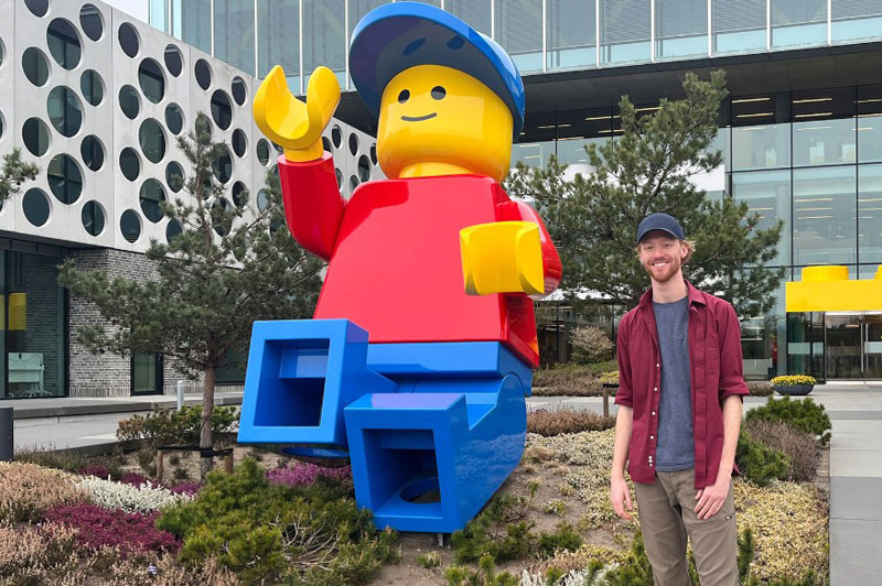 A person stands next to a large LEGO figure outside the LEGO House.