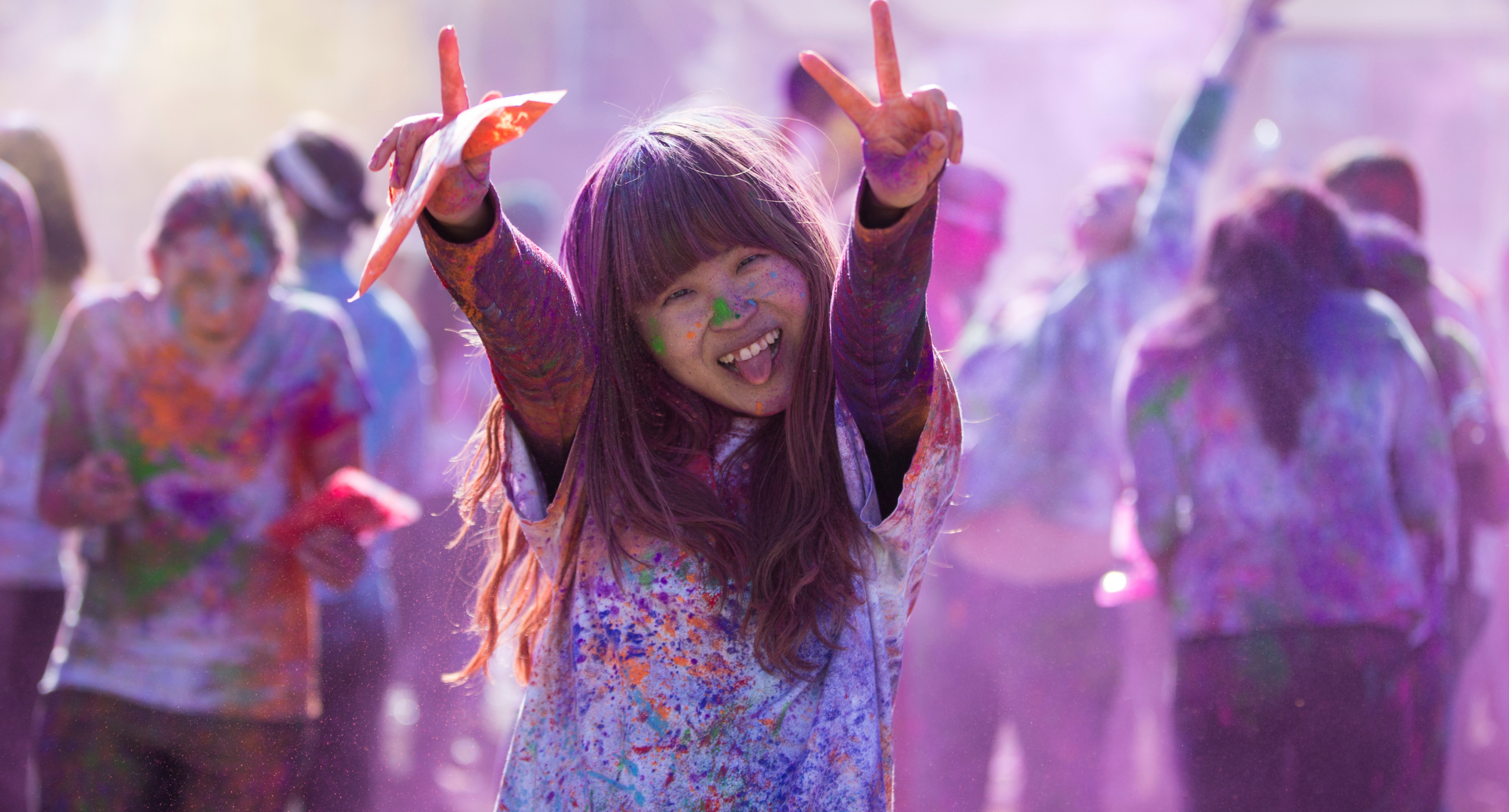 Student showing peace signs at a color festival outdoors