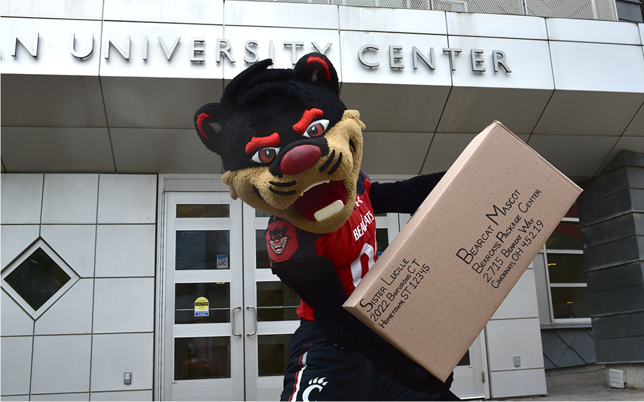 Bearcat Mascot near student center entrance holding package