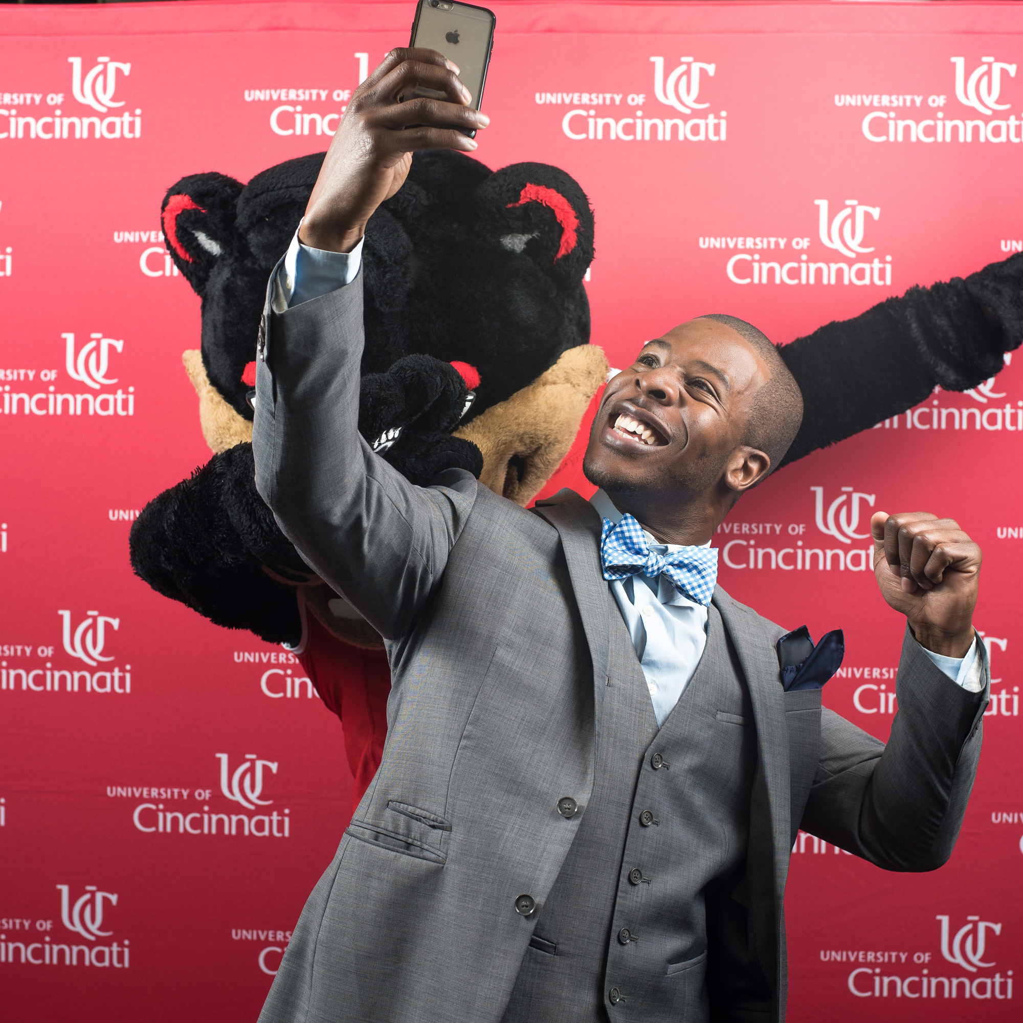 A UC Alum poses for a selfie with the Bearcat mascot