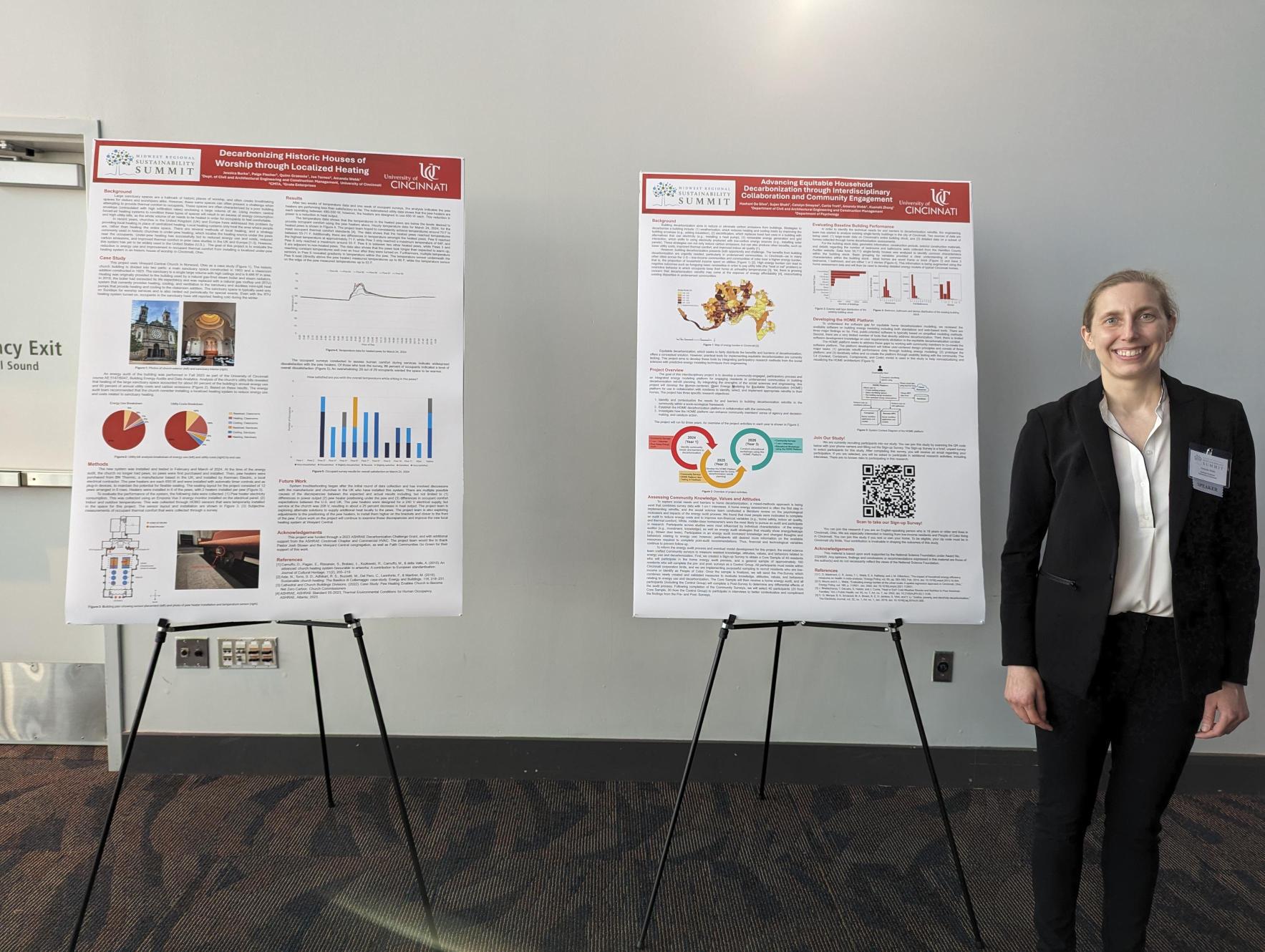 Amanda Webb stands next to two posters displaying her work. 