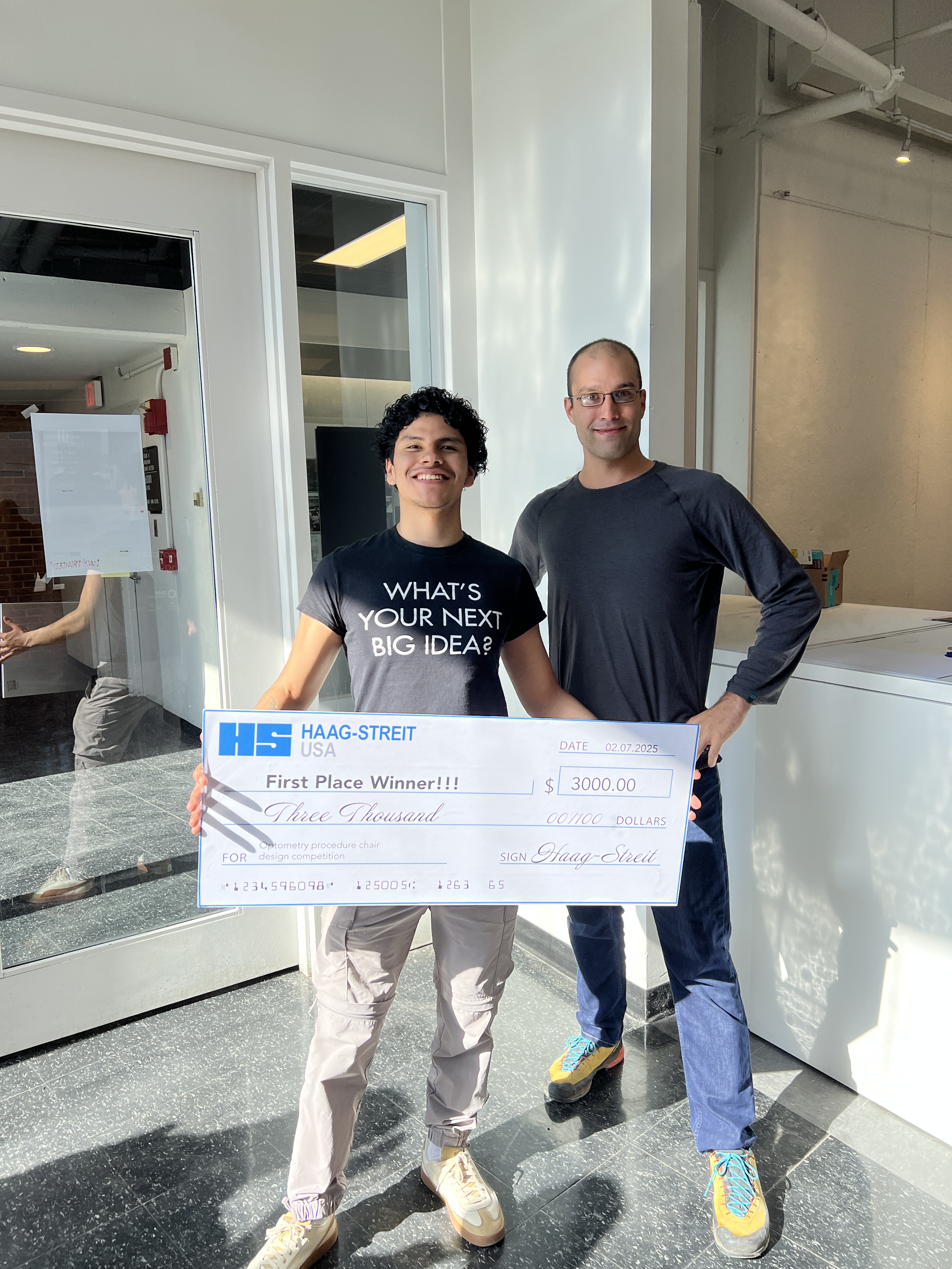 Caleb Loayza and Guy Mueller hold a giant check after their competition win. 