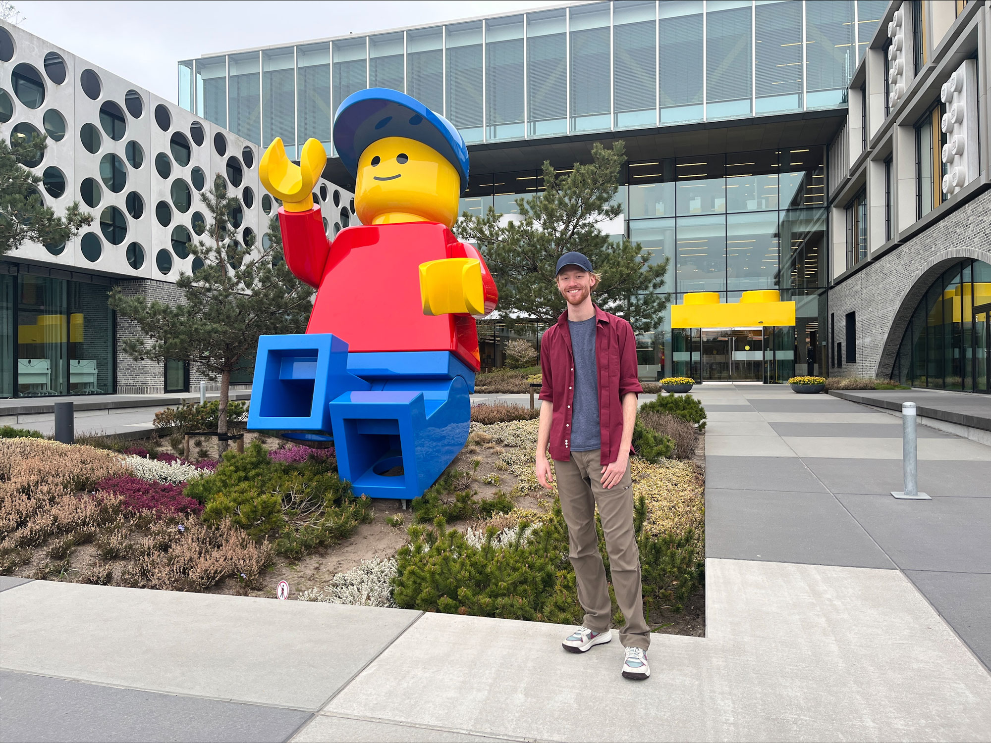 UC Student Adam Wolshire poses next to a life-sized Lego Minifigure outside the Lego headquarters.