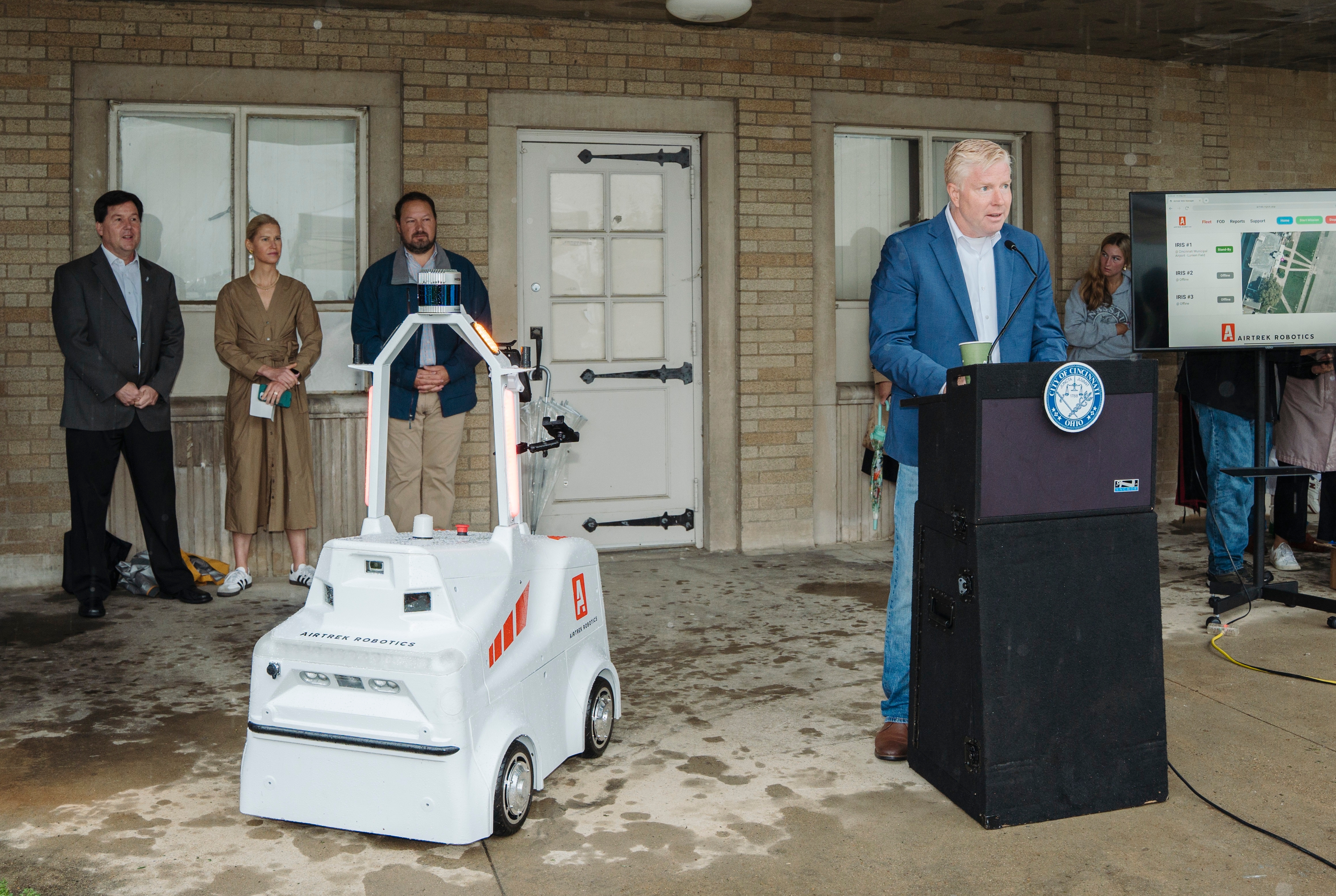 Councilmember Mark Jeffries at podium with Airtrek Robot, IRIS.