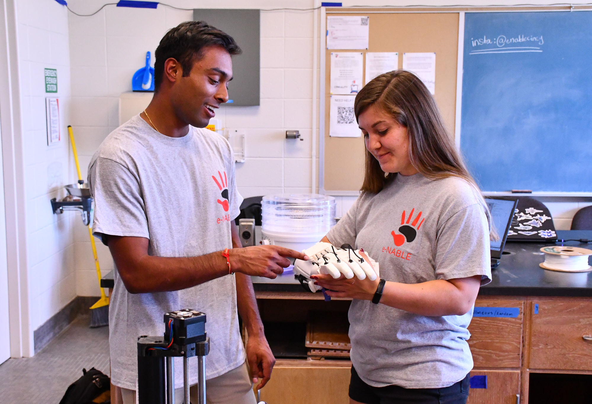 Teresa Hawk holds a prosthetic arm and another student points at it. 