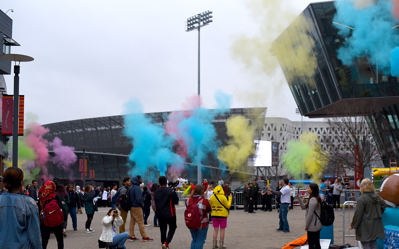 Puffs of blue, yellow and pink smoke above students on MainStreet.