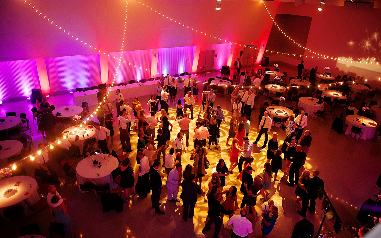 Overhead view of lighted dance floor with banquet tables and people dancing.