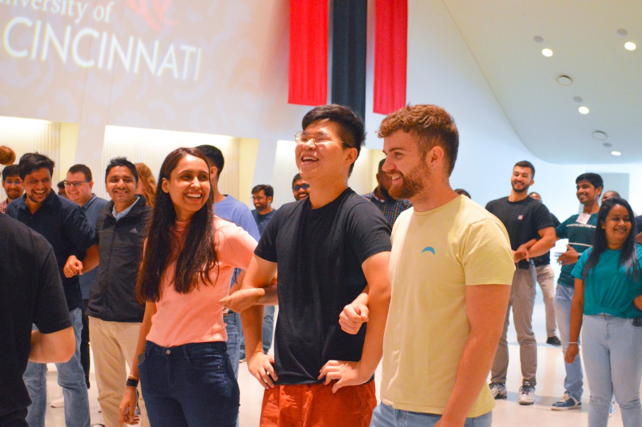 A group of international students link arms at an orientation event.