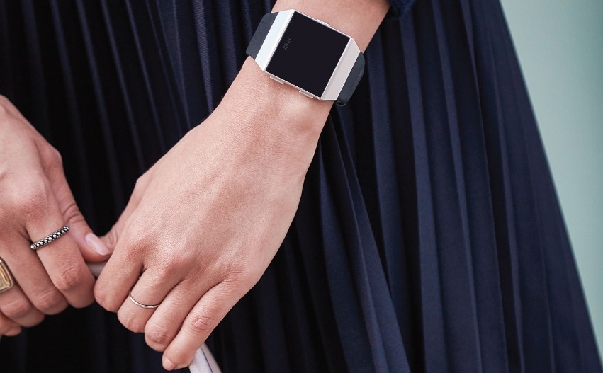 The hands of a woman wearing a fitbit watch