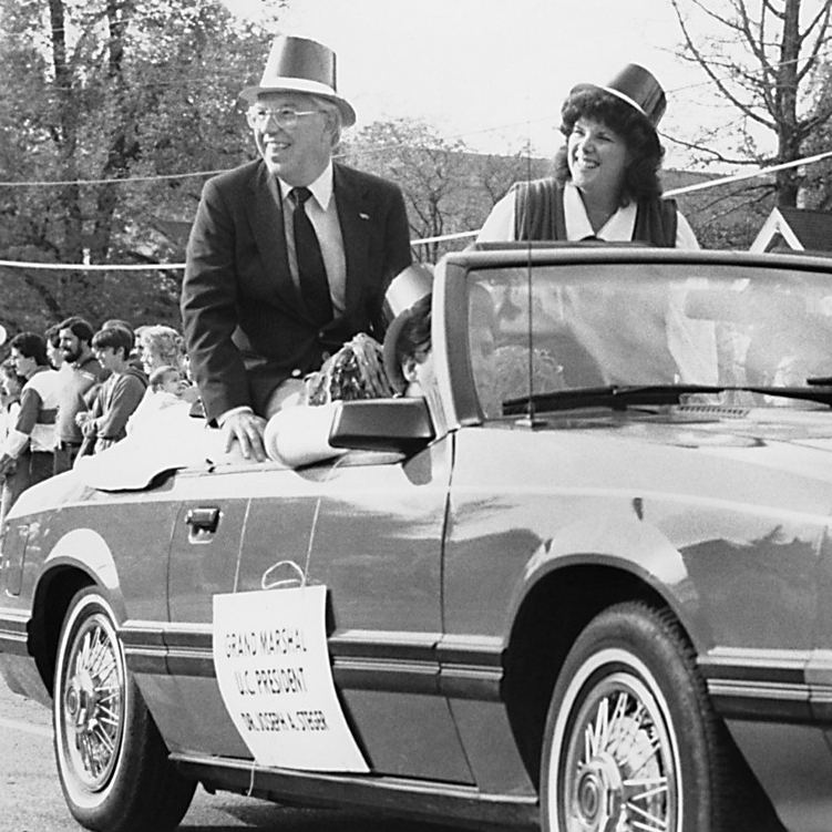 Carol Steger and Joseph Steger ride in a car in a parade