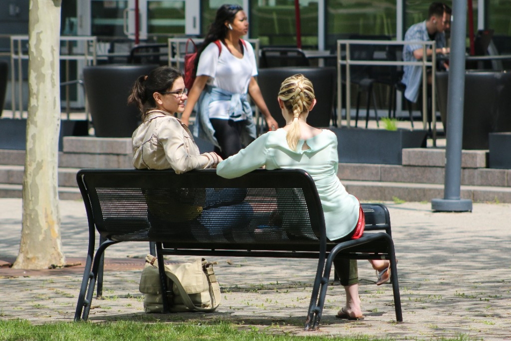 Two students sitting at bench talking