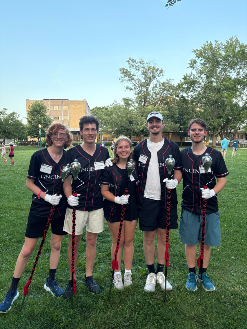 A group of 5 college students holding drum major maces