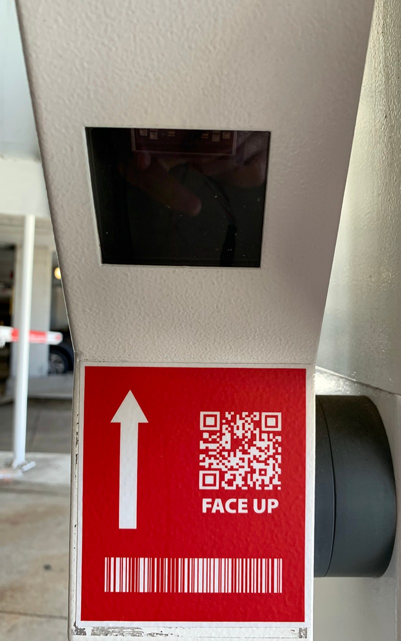 Bar code scanning equipment that sits to the left of the exit station. An arrow points up with a QR code, indicating that is where the ticket can be scanned.