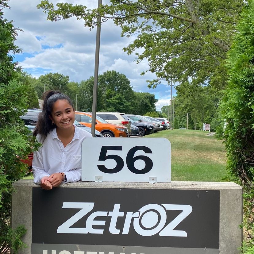 A female student poses in front of the sign outside her co-op placement