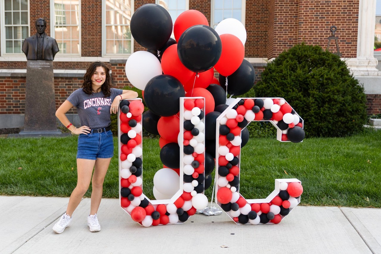 Student poses with a large block U-C filled with red, white, black balloons