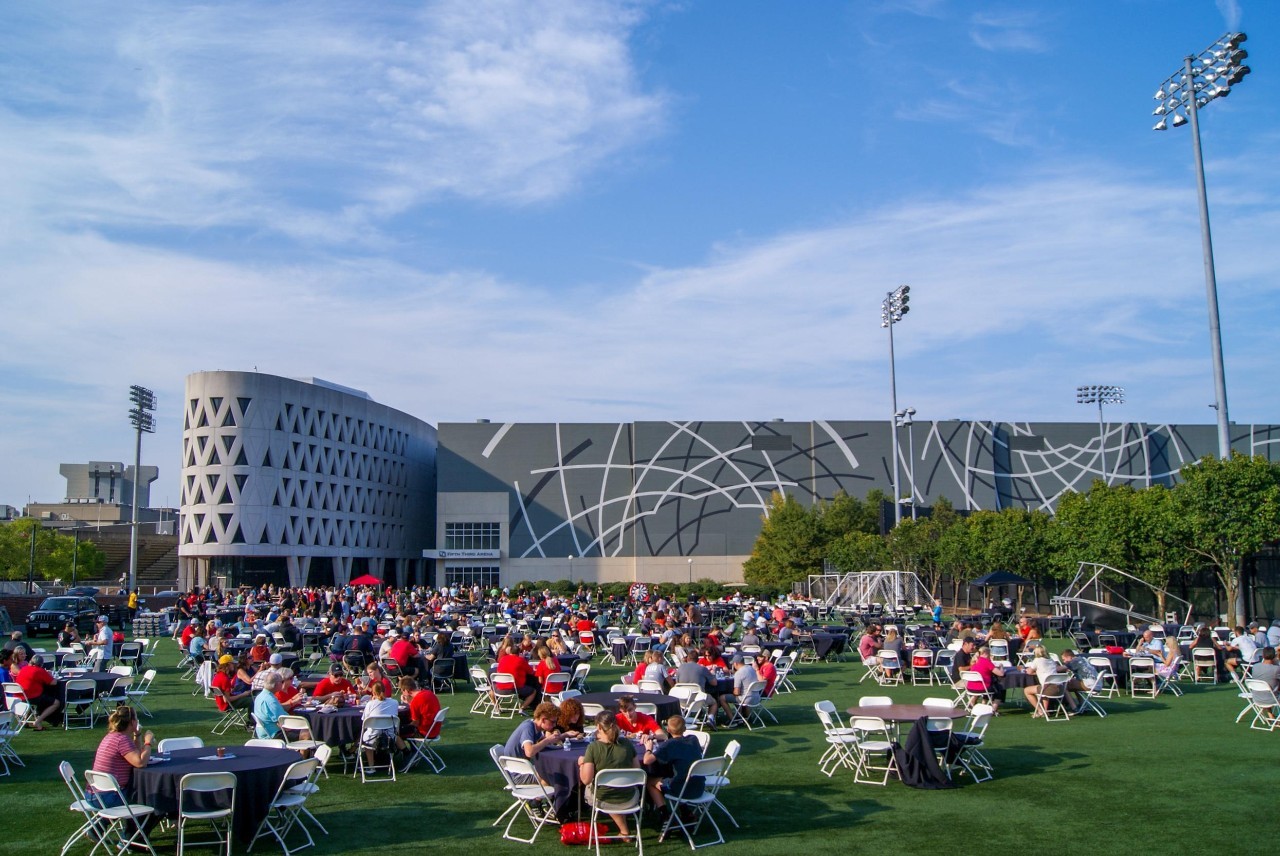 Hundreds of families seated on Sheakley Lawn in front of Lindner Athletic Center for a BBQ