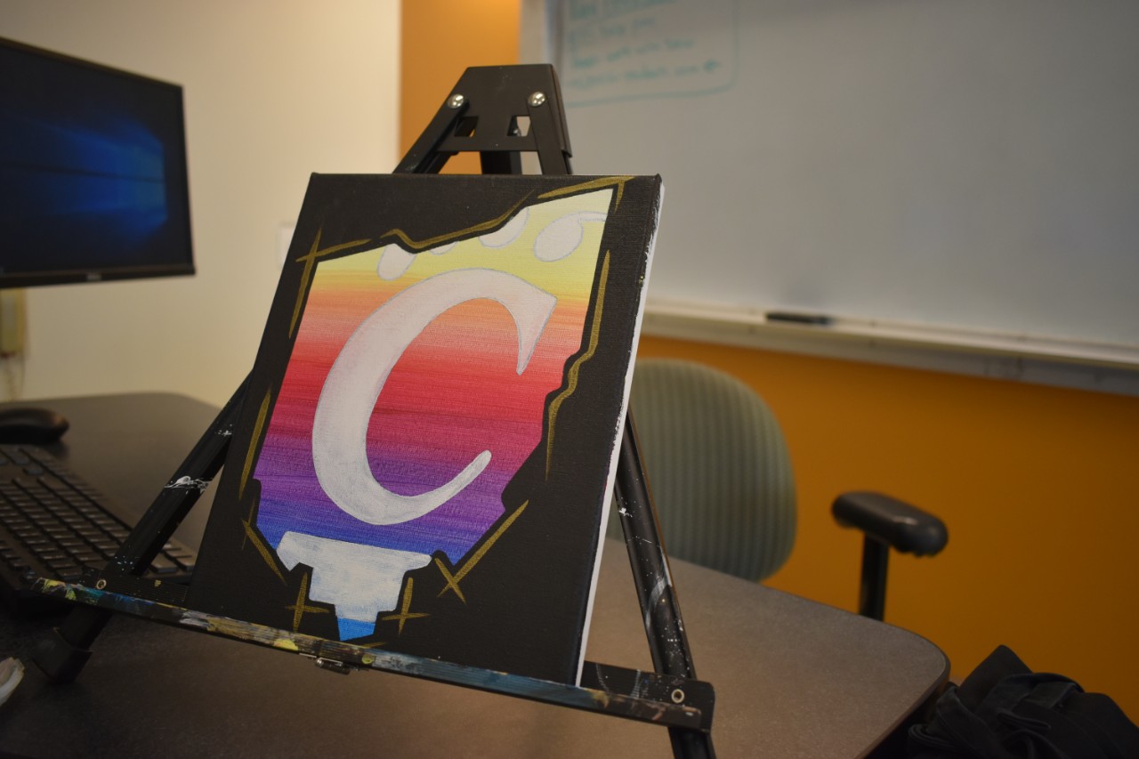 A painted canvas of a C-Paw sitting on a small easel