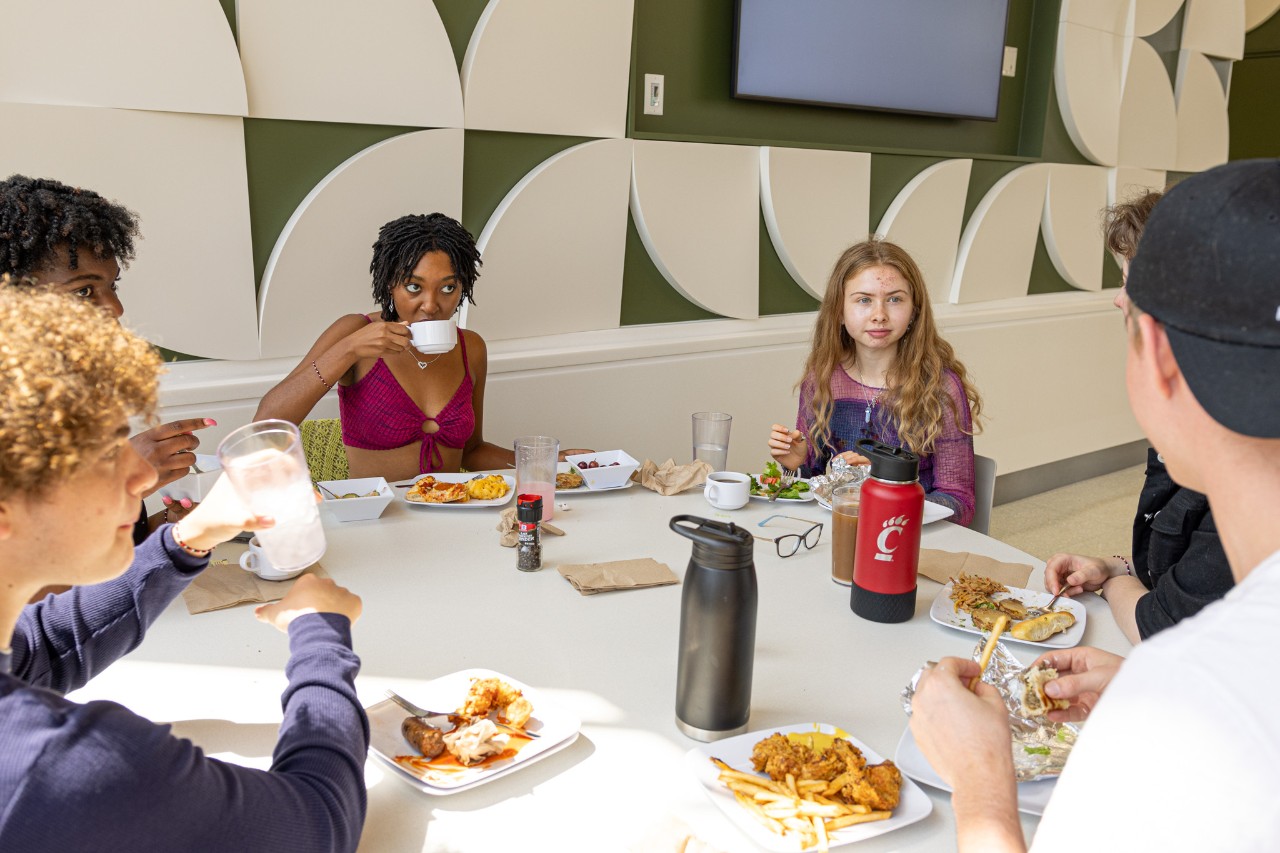 Students in the buffet line at a UC dining facility. A student on the right is using a pair of silver tongs to put salad on her plate.