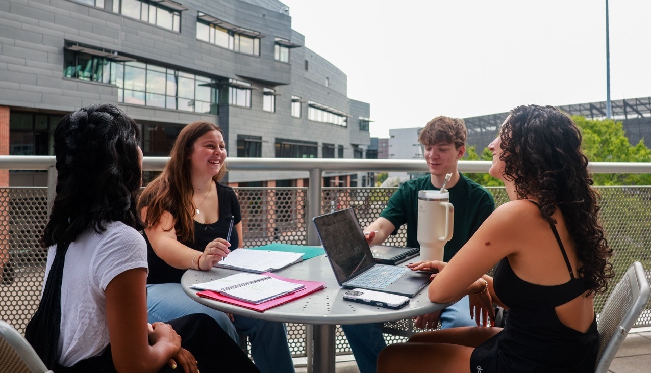 4 students sitting on a balcony meeting on Main Street