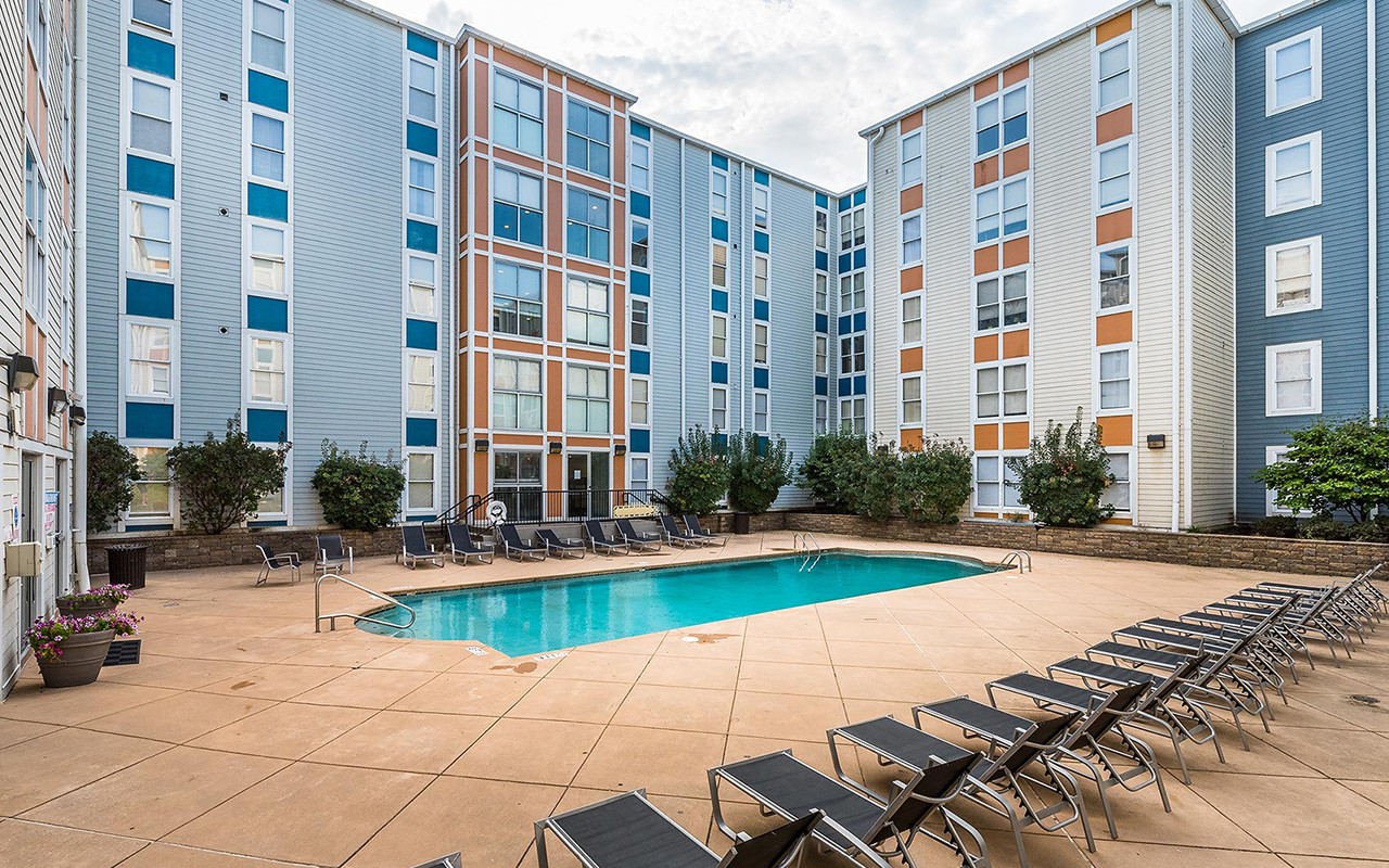 Courtyard featuring landscaping, swimming pool and reclining chairs.