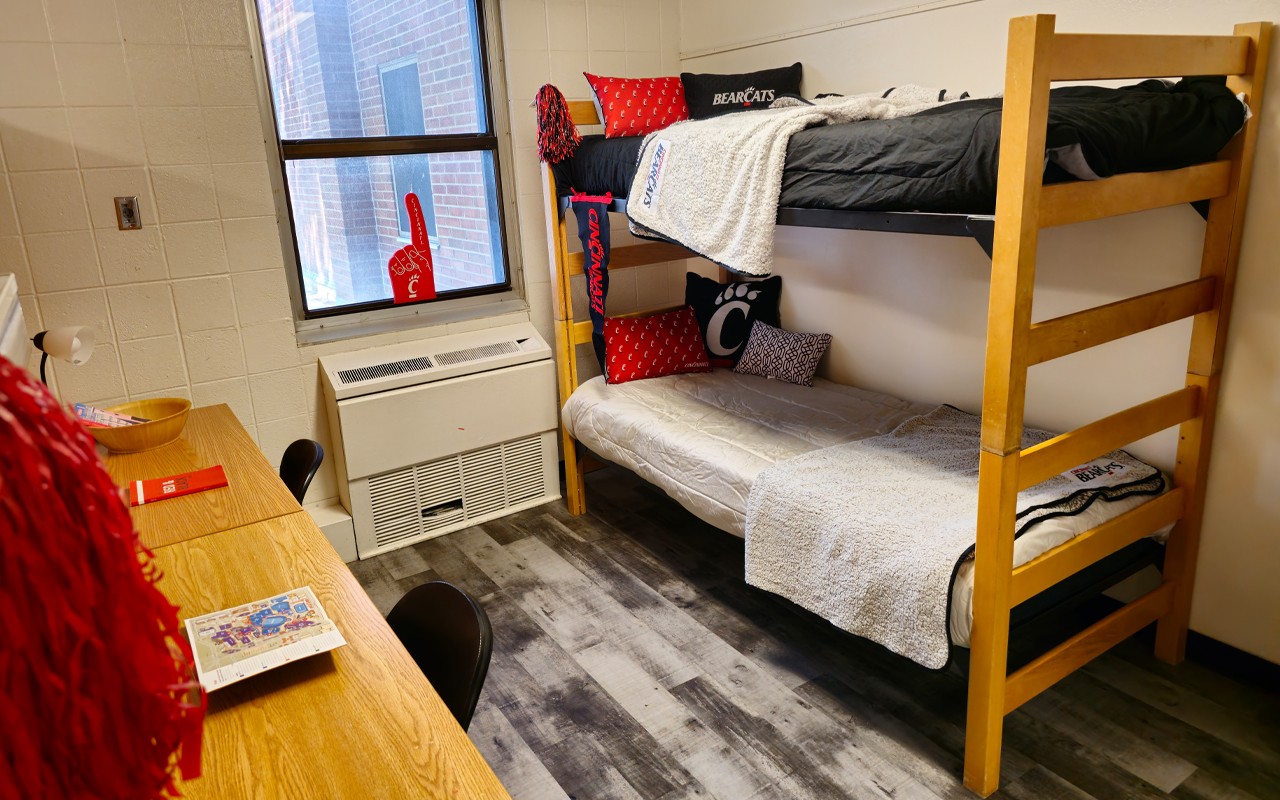 Bunk bed against right wall with desks across the room