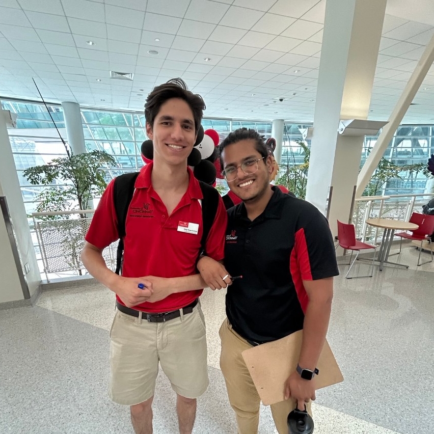Two Student Orientation Leaders locking arms, posing for picture inside a building