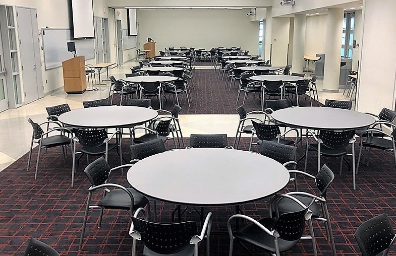 Large meeting room set up with round tables and chairs. There is a podium at the center of the room