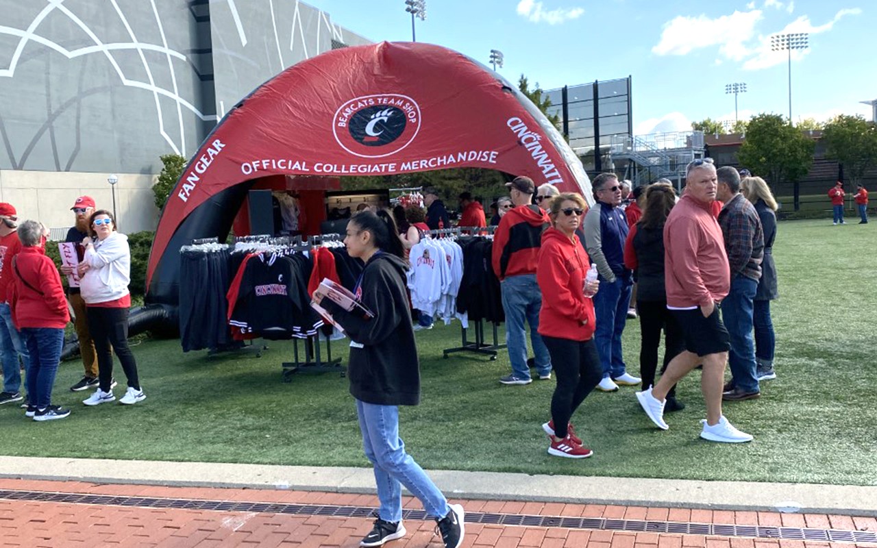 Red and black tent shop and Bearcats fans on Shaekley Field