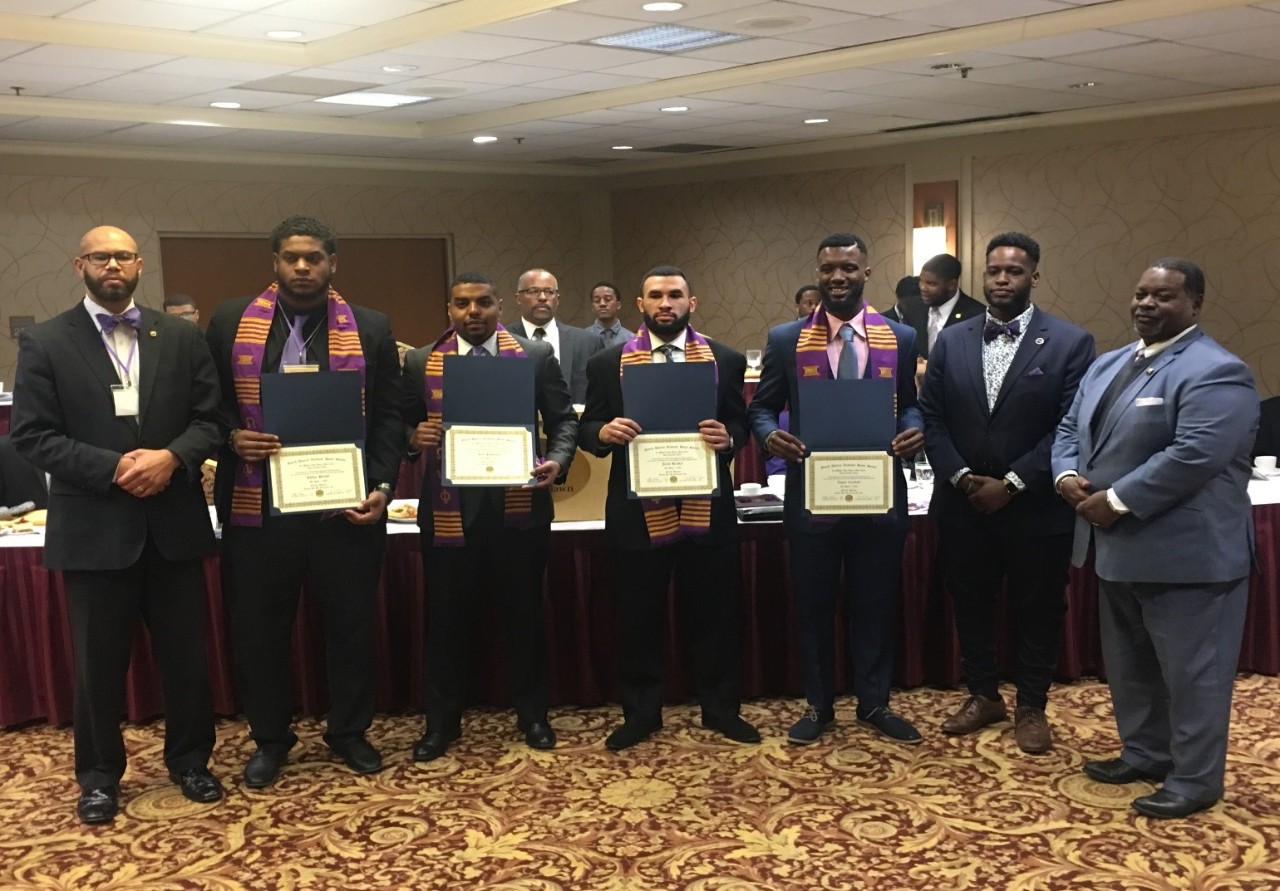 The UC Bearcat mascot poses next to the UC Bearcat statue.