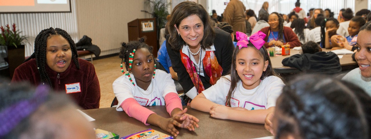 UCPD officer and several middle school girls stand around UC's Bearcat statue outside Fifth Third Arena
