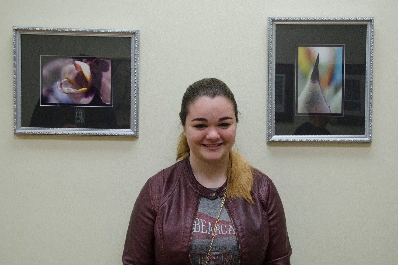 A female student posing at the art gallery with her artwork