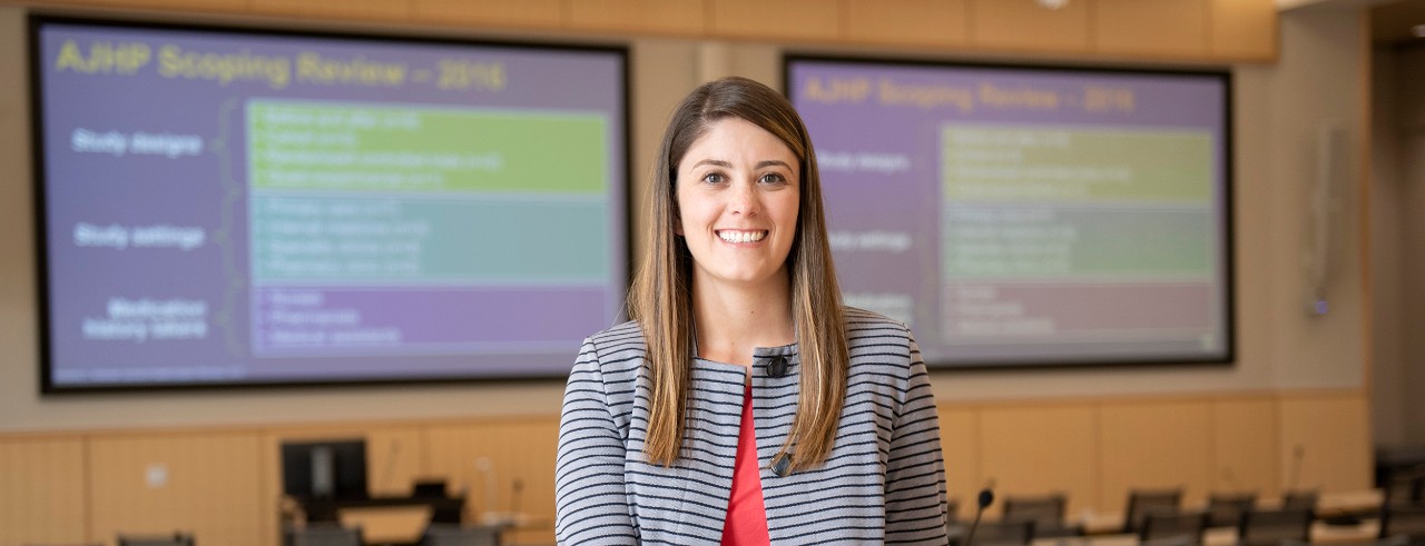 Elizabeth Berryman, PharmD, sitting on a desk in the Kowalewski Hall auditorium 