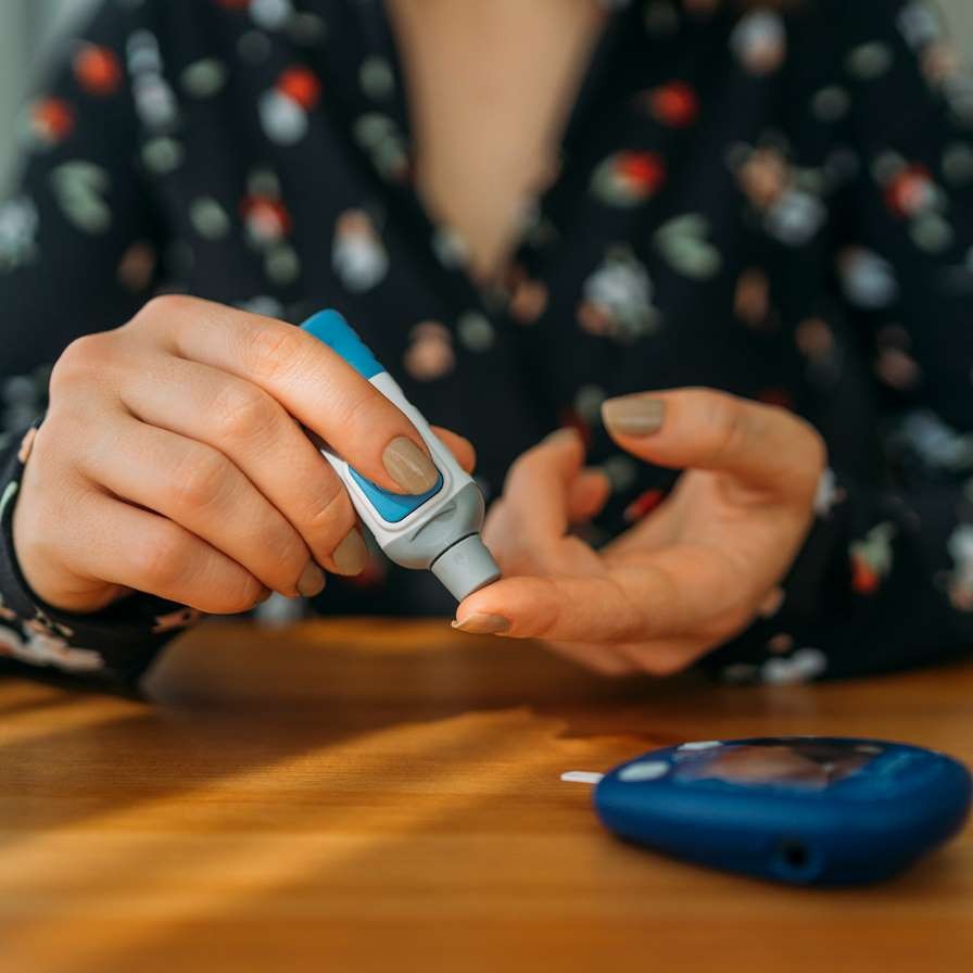 Woman sticking her finger with a diabetes testing device