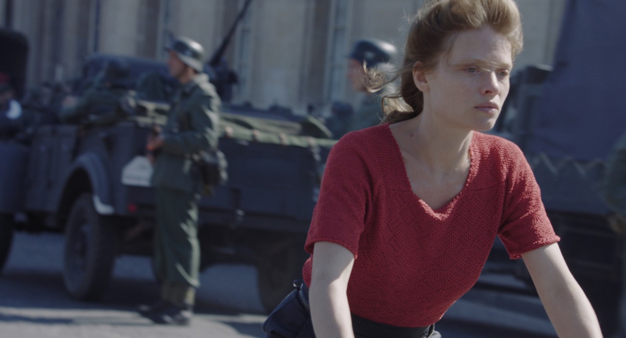Young woman riding bike near soldiers