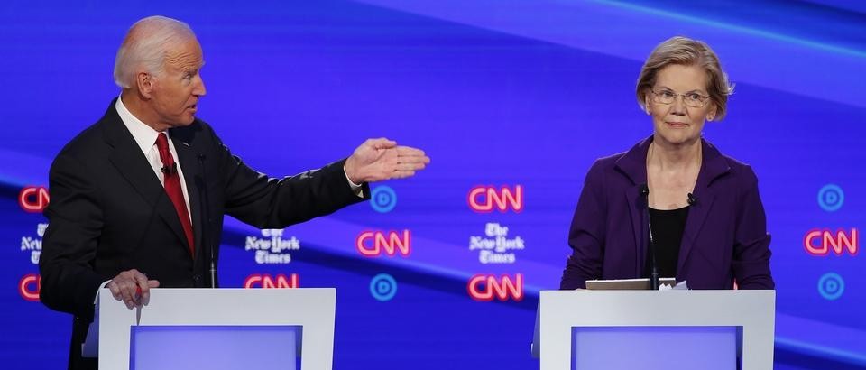 a man at a podium gestures to a woman at a podium
