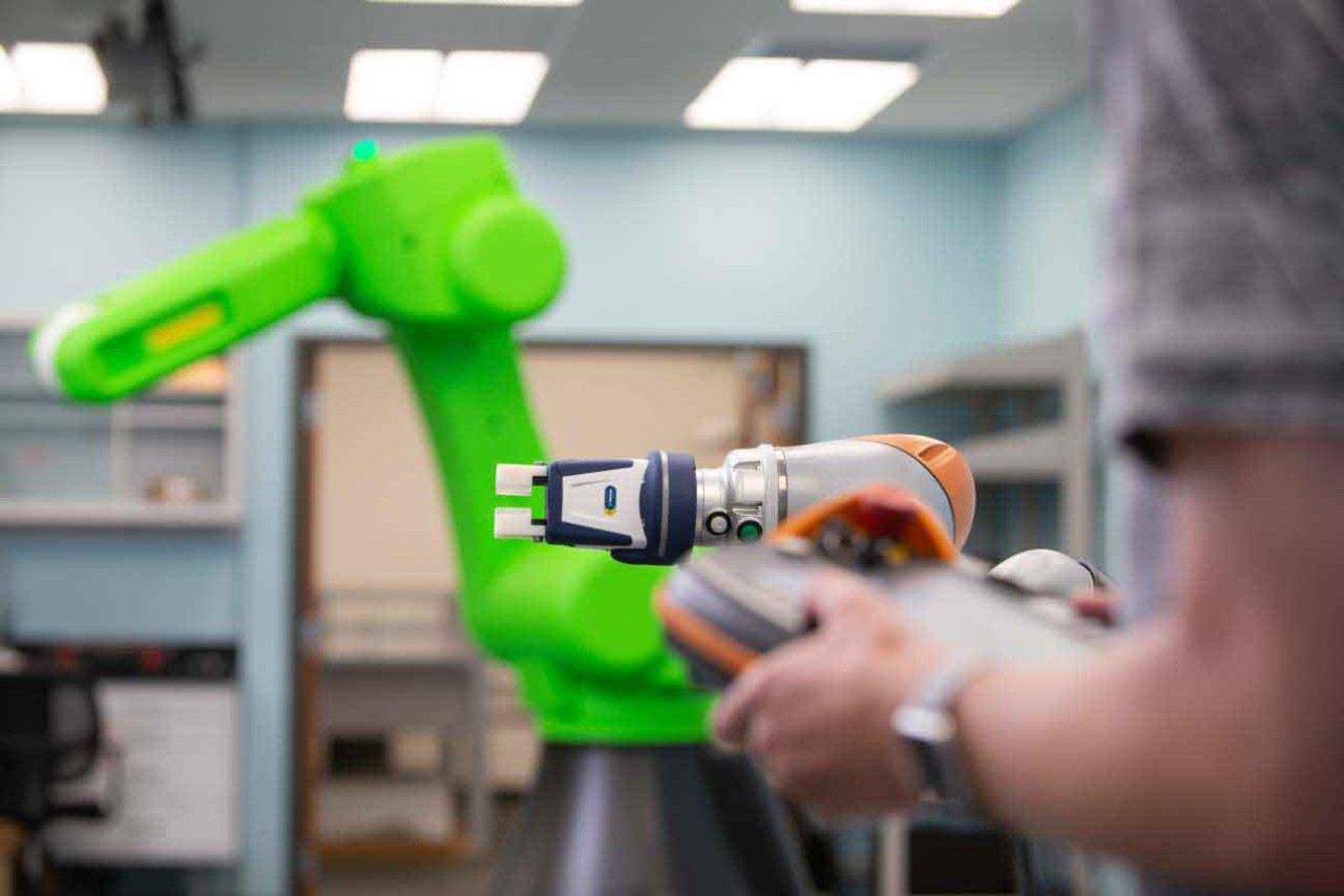 A closeup of a remote control with a large robotic arm in the background.