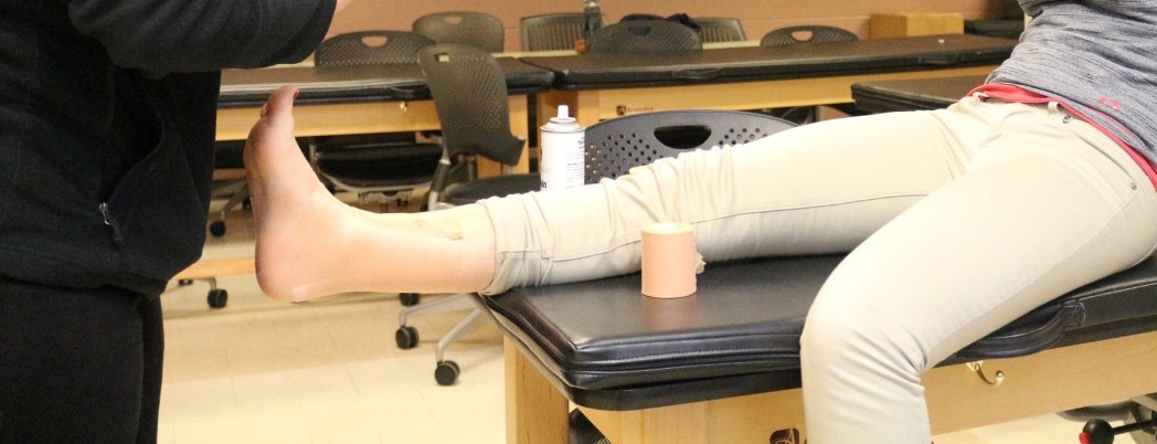 An athletic trainer wraps a patient's ankle