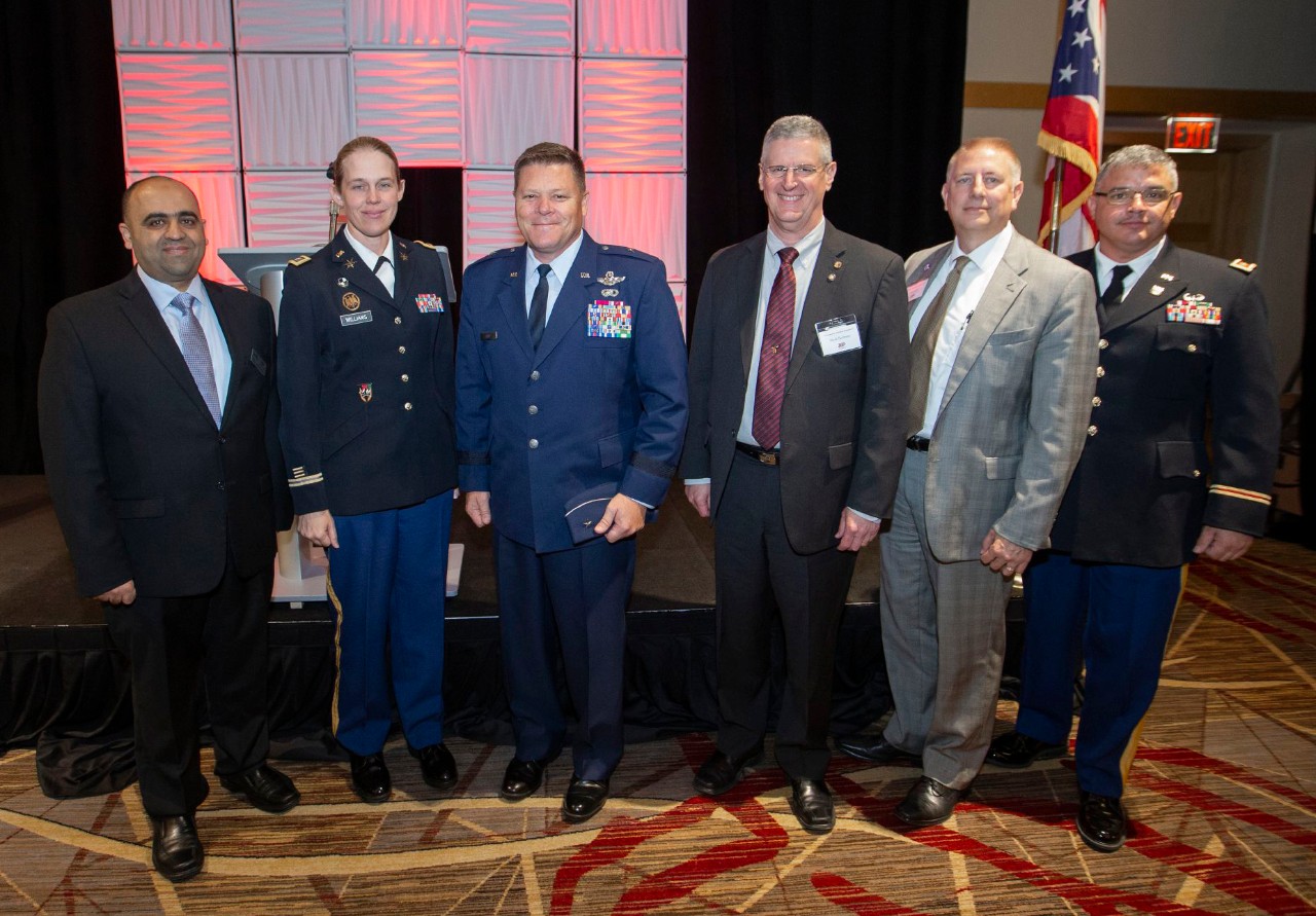 Six people stand in a row posing for the camera