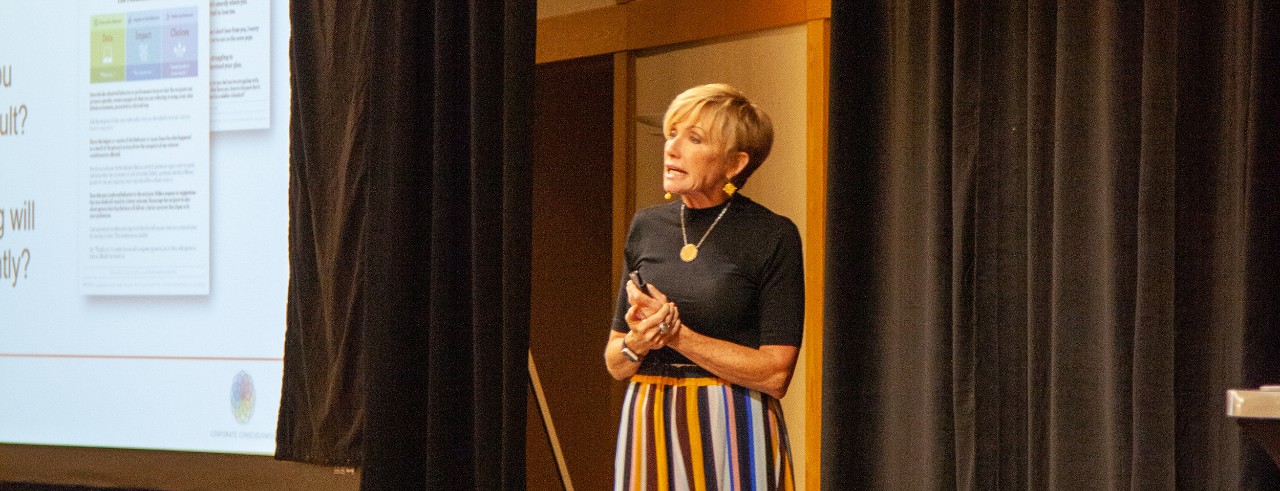 Deni Tato speaking at an event.