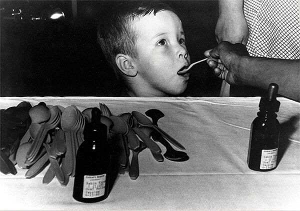 A young boy receives a dose of live polio vaccine from a spoon in the 1960s.