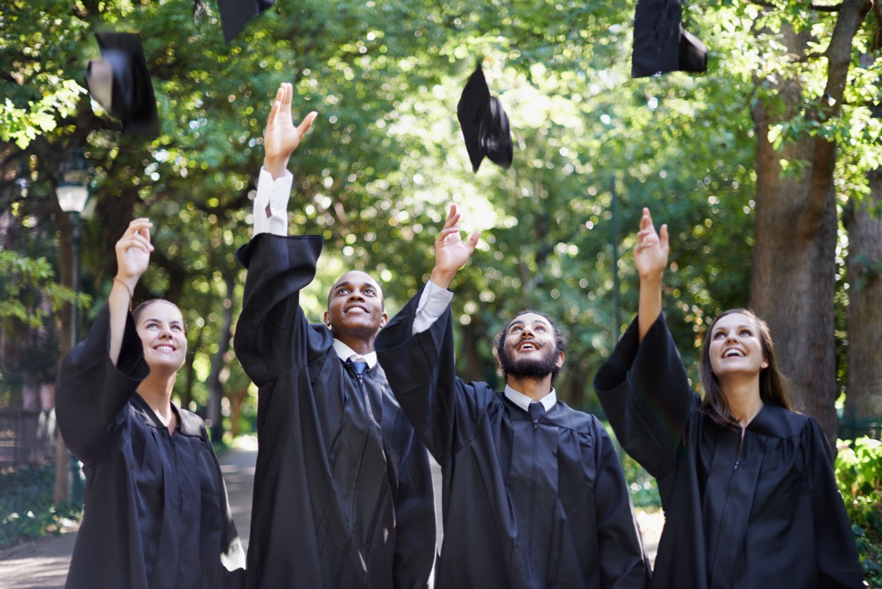 students throw graduation cap in air