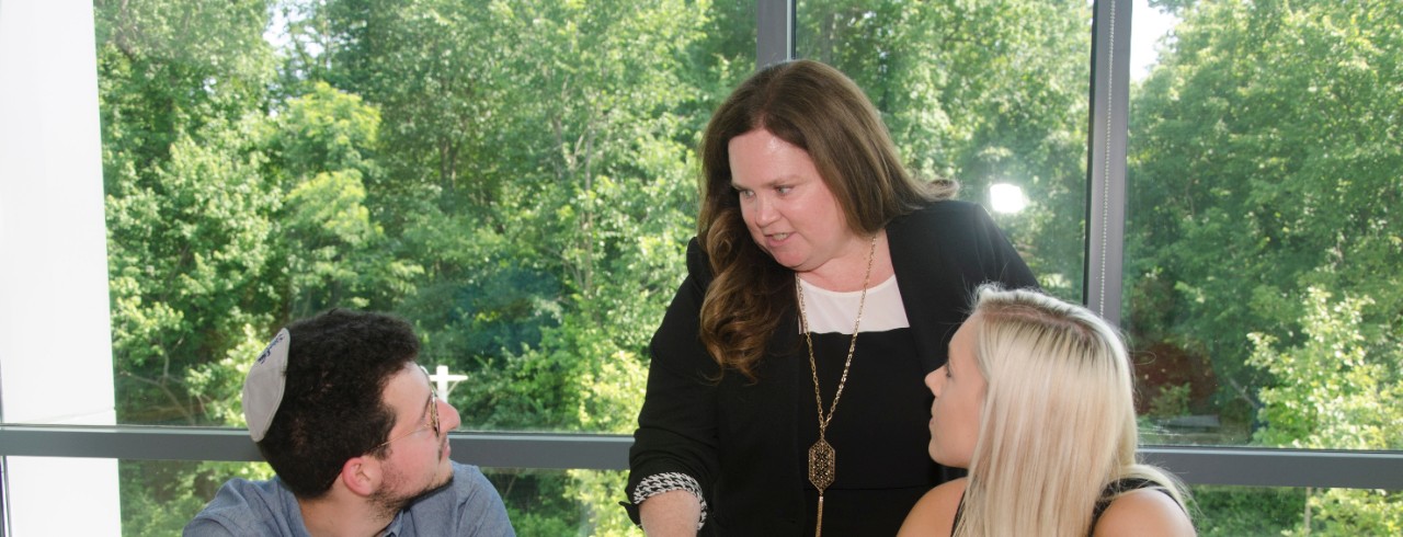 Two students with Professor Wendy Calaway in a classroom