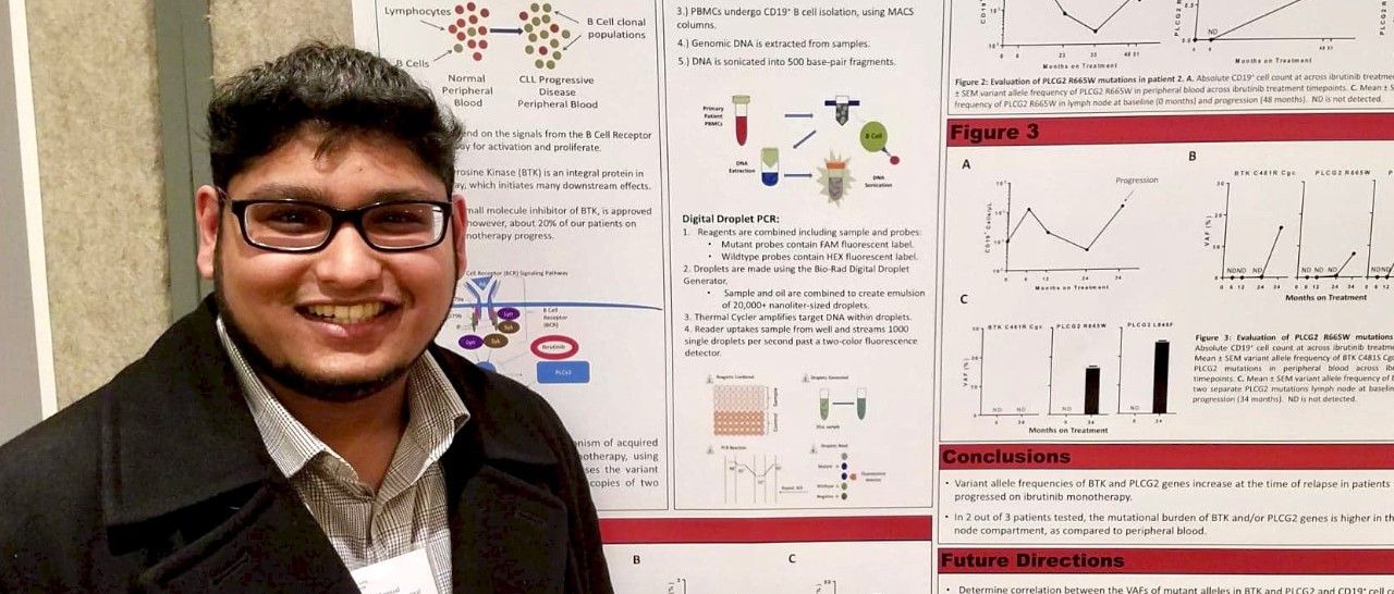 UC grad student Dylan David stands next to a poster at a scientific conference.