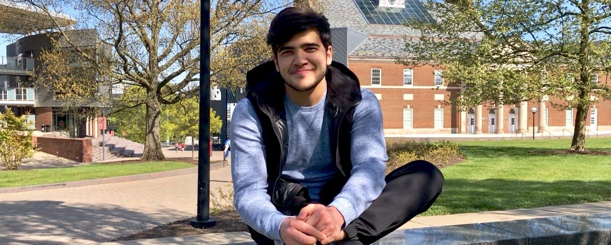 UC business student Komronbek Rakhimov sits on UC's campus in front of TUC.