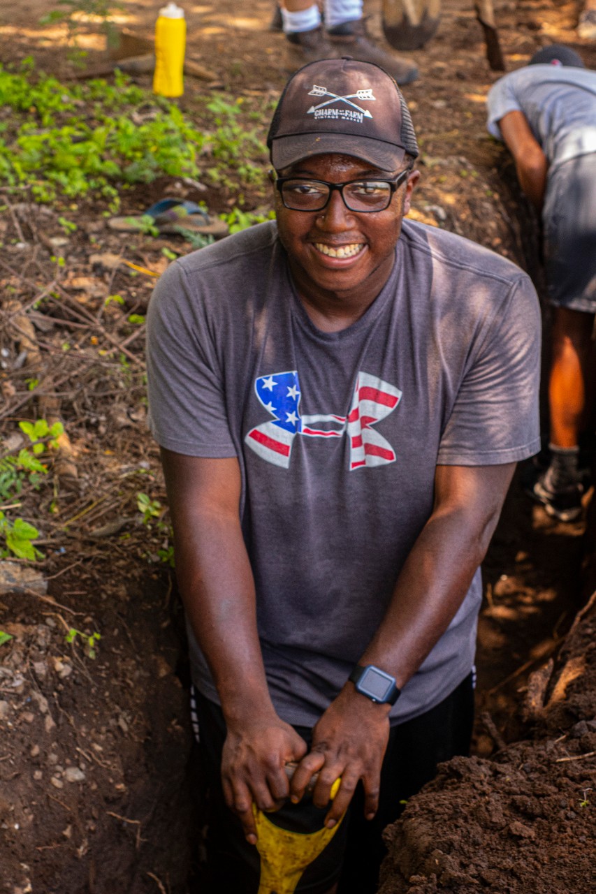 A young man poses for a photo holding a shovel