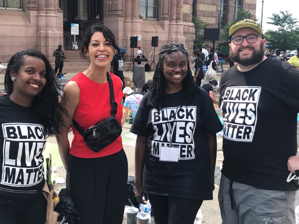 UC DAAP artists Adoria Maxberry, professor Flavia Bastos, Latausha Cox and Ryan Tinney stand together in front of the Black Lives Matter! mural they helped to paint.