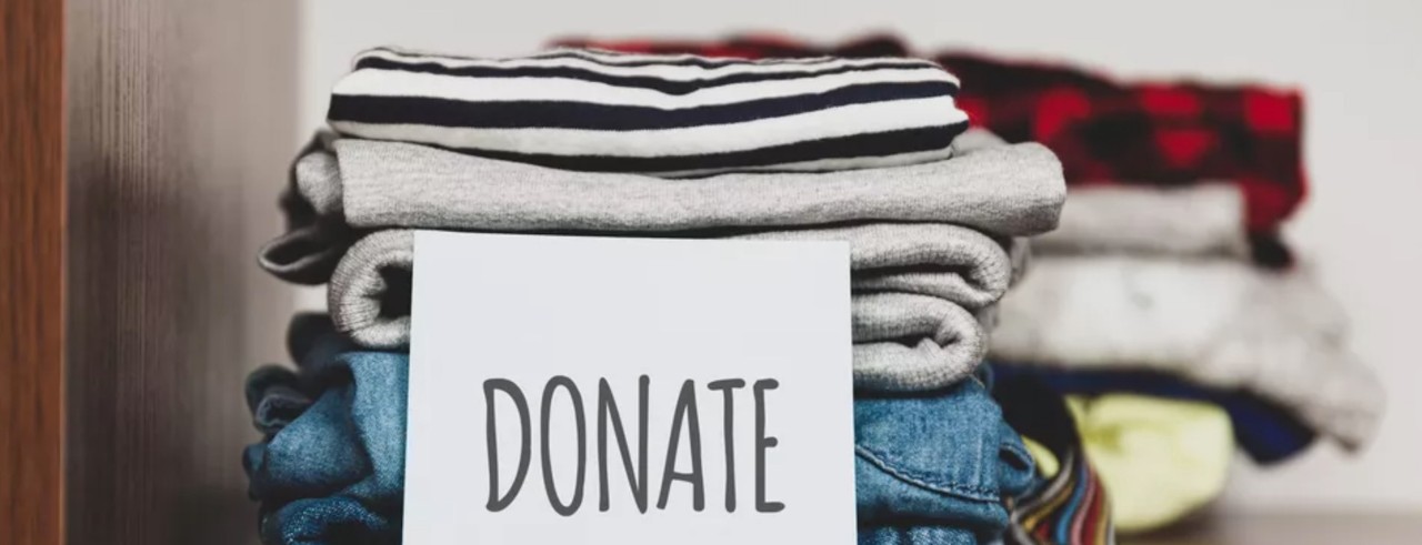 stack of folded clothing with a donation sign